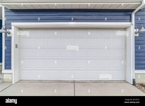 Wide White Wooden Garage Door Against Blue Exterior Wall Siding Of