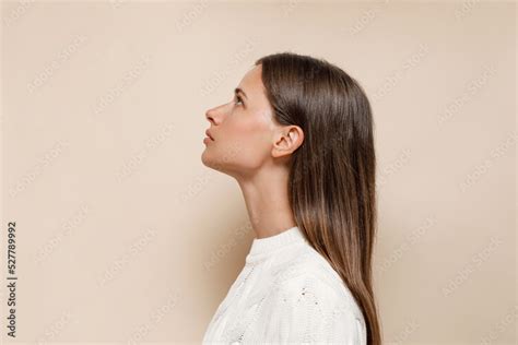 Caucasian Female With Long Shiny Hair With Nude Makeup In Profile On A Beige Background Stock