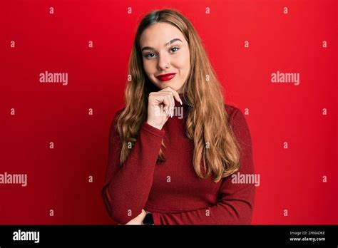 Jeune femme blonde portant un chandail à col roulé en regardant avec confiance la caméra avec le