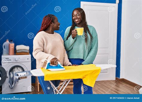 African American Women Ironing Clothes Drinking Coffee At Laundry Room