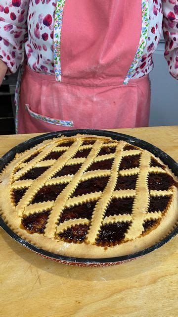 A Pie Sitting On Top Of A Wooden Table Next To A Woman In An Apron