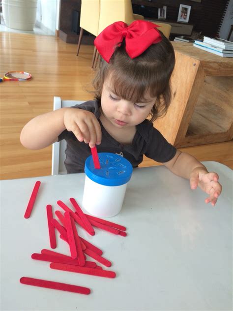 Encaixando os palitos de picolé no potinho Atividade montessoriana