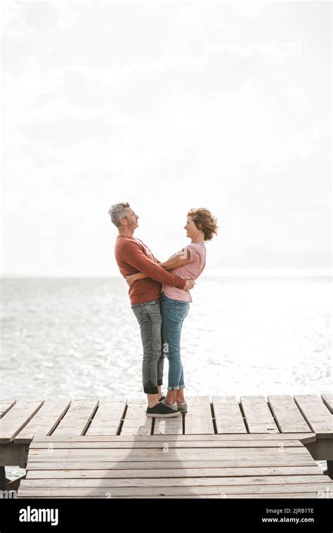 Loving Mature Couple With Arms Around Each Other Standing On Jetty