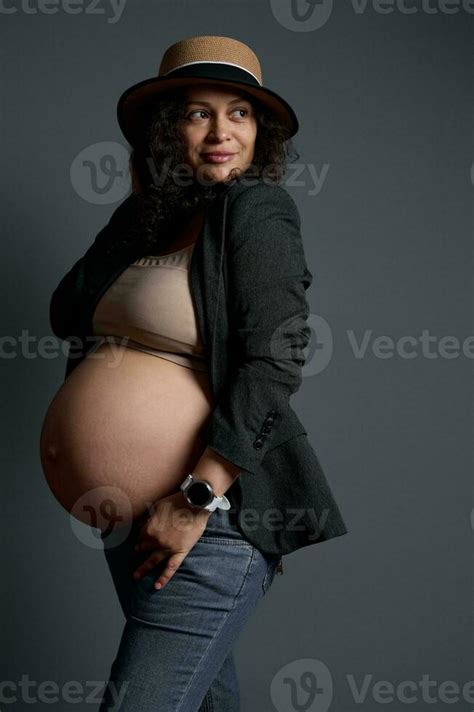 Stylish Pregnant Woman With Big Naked Belly Dressed In Jeans Blazer And Straw Hat The Concept