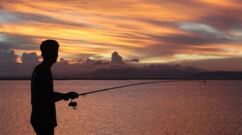 Silueta De Un Pescador Con Una Ca A De Pescar En El Lago Al Atardecer