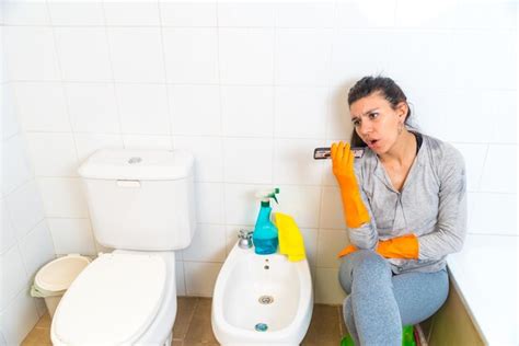 Joven latina limpiando el baño jugando enojada hablando por teléfono Foto Premium