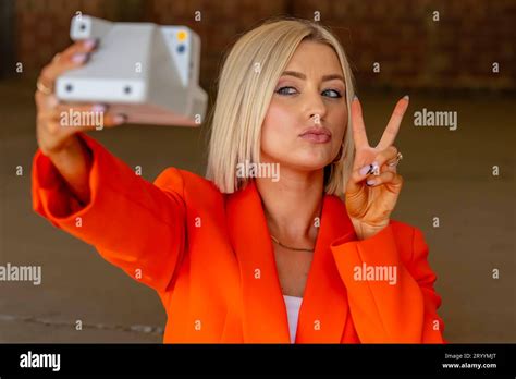 A Lovely Blonde Model Poses Outdoors Using Her Camera While Enjoying The Spring Weather Stock