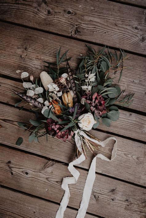 The Bridal Bouquet Is Laid Out On Top Of The Wooden Planks With White