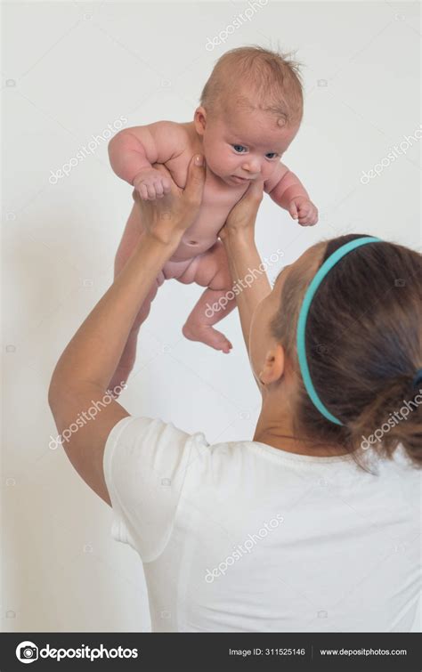 Portrait Of A Woman Holding A Naked Baby In Her Arms Raised High Above