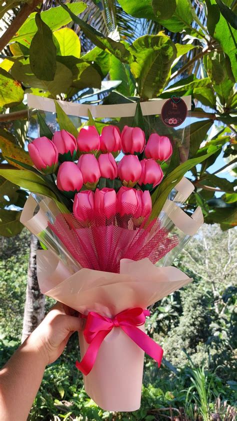 A Bouquet Of Pink Tulips Is Being Held Up By Someone S Hand