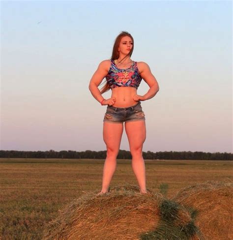 A Woman Standing On Top Of A Hay Bale In A Field With Her Hands On Her Hips