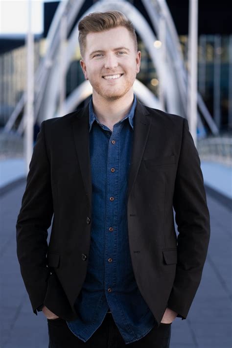 a man standing in front of a bridge wearing a suit and smiling at the ...