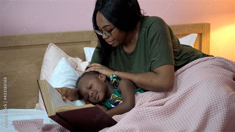 african american mother singing lullaby for little daughter before ...