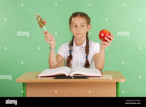 Fille Dans Un Uniforme Scolaire Assis Au Bureau Et Choisir Des Bonbons