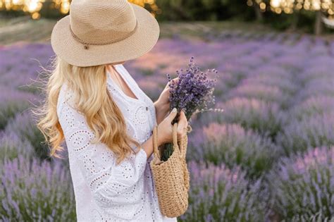 Mujer en campo de flores de lavanda al atardecer en vestido púrpura