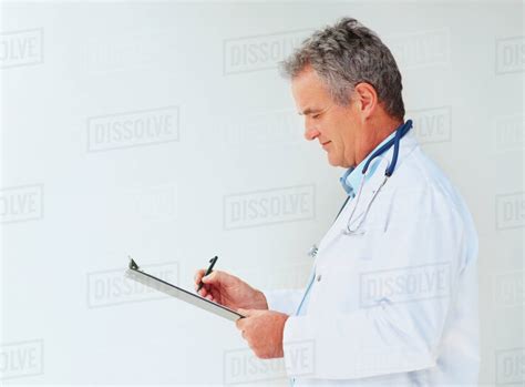 Doctor Writing On Clipboard Stock Photo Dissolve