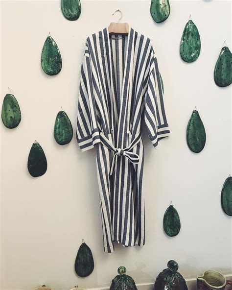 A Striped Robe Hanging On A Wall Next To Pears And Other Green Objects