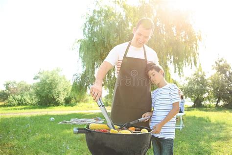 Little Boy With His Father Cooking Tasty Food On Barbecue Grill