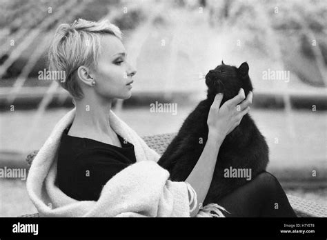 eine schöne blonde Frau mit einer schwarzen Katze hält eine schwarze Katze eine Katze