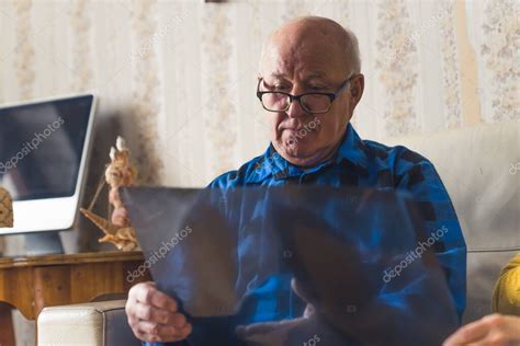 Concerned Old Wrinkled Bald Man In A Blue Flannel Shirt And Black