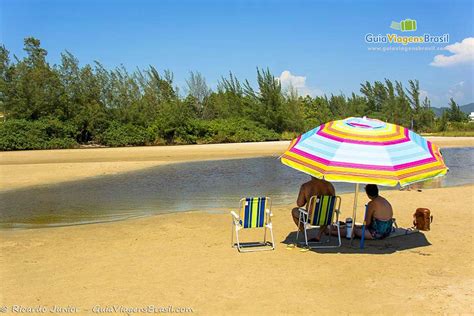 Imagem De Casal Se Protegendo Do Sol Em Baixo Do Guarda Sol Admirando A