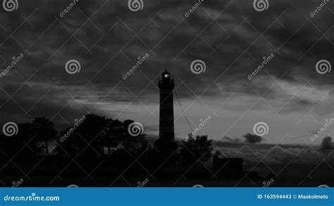 Lighthouse Shines In The Dark With A Dramatic Sky Silhouette Of