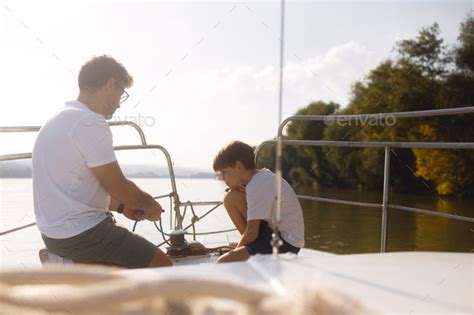 Young Caucasian father teaching his son to tie sail knots Stock Photo by StockRocketStudio