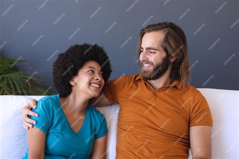 Premium Photo Happy Diverse Couple Sitting On Sofa Embracing And