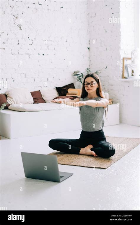 Beautiful Brunette Fitness Woman Make Stretching Exercises In Front Laptop Doing Yoga Indoors