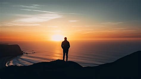 Premium AI Image A Man Stands On A Cliff Overlooking The Ocean At Sunset