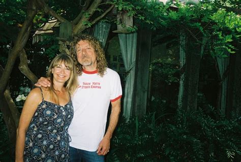 a man standing next to a woman in front of trees