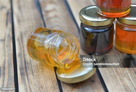 botol kecil penuh tumpahan madu segar  atas meja kayu foto stok