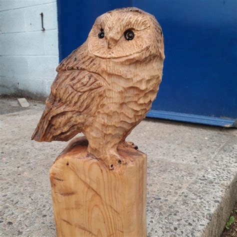 An Owl Statue Sitting On Top Of A Wooden Post In Front Of A Blue Door