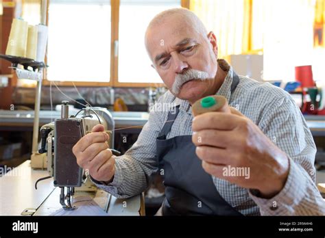 senior man threading  fashioned manual sewing machine stock photo