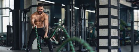 Naked Muscular Man Exercising With Battle Ropes At Gym Stock Photo