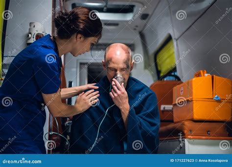 Doctor Stands With Man Who Sits In Oxygen Mask In Blanket Stock Image