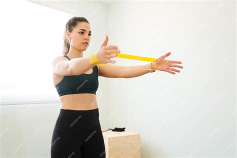Спортивная молодая женщина держит на руках желтую резинку сопротивления ...