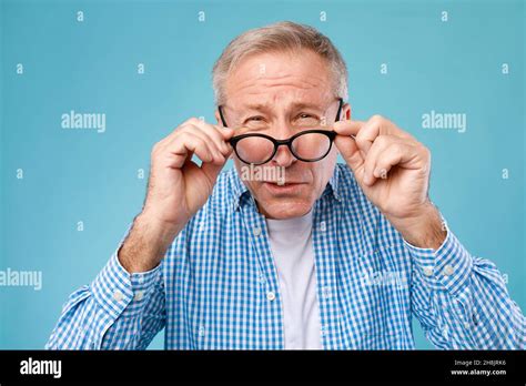 Mature Man Squinting Wearing Eyeglasses Looking At Camera Stock Photo