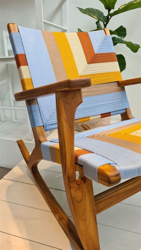 A Wooden Rocking Chair Sitting On Top Of A White Floor Next To A Potted