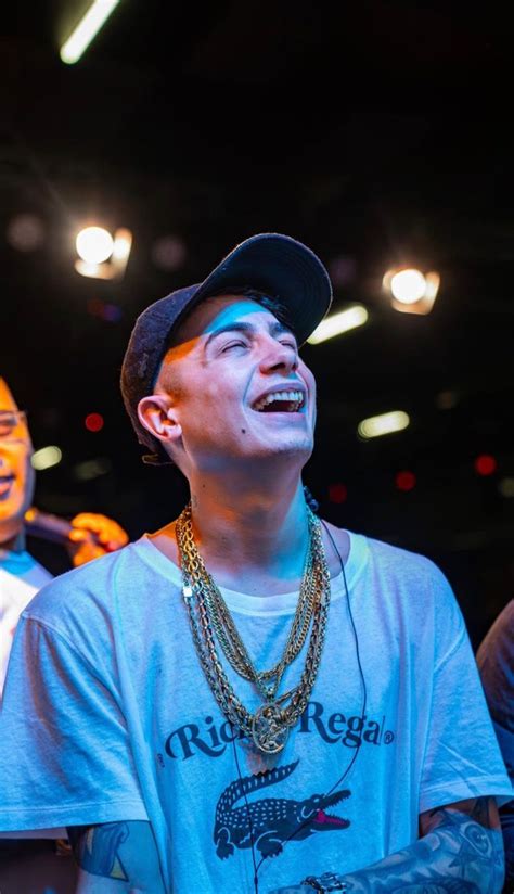 A Man With His Eyes Closed Wearing A Hat And Some Necklaces In Front Of Him