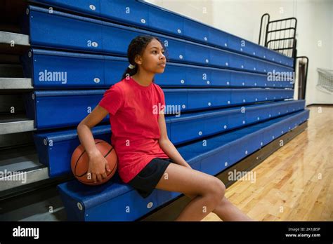 Junior High Girl Basketball Player At Bleachers In Gymnasium Stock