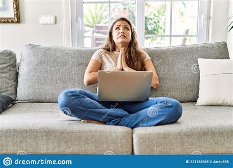 Beautiful Young Brunette Woman Sitting On The Sofa Using Computer Laptop At Home Begging And