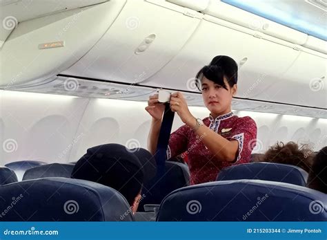 A Female Flight Attendants On The Aisle Show Passengers About Safety