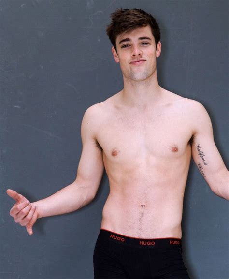 A Shirtless Man With His Arms Out In Front Of A Gray Wall Wearing Black