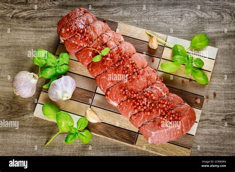 Raw Rib Eye Beef Steak With Garlic And Herbs On A Wooden Background