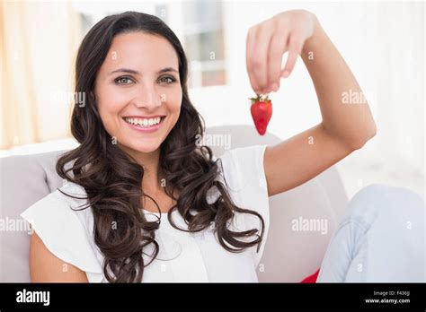 Pretty Brunette Eating Strawberries On Couch Stock Photo Alamy