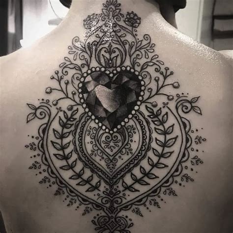 the back of a woman's neck with an intricate tattoo design on her shoulder