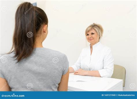 Blonde Ärztin in Einem Weißen Mantel an Einem Tisch in Einem