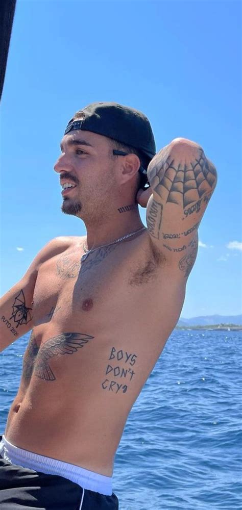 A Shirtless Man With Tattoos On His Arm And Chest Standing In Front Of