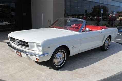 An Old White Mustang Convertible Parked In Front Of A Building